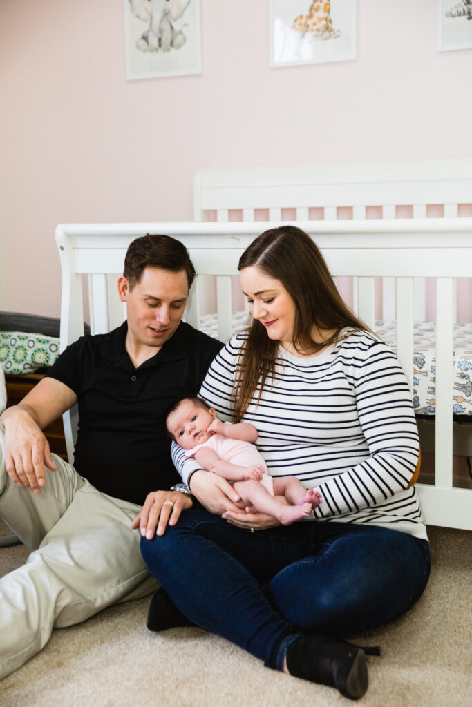 Parents look at their baby during their Phoenix In-Home Newborn session by Arizona wedding photographer Juniper and Co Photography.