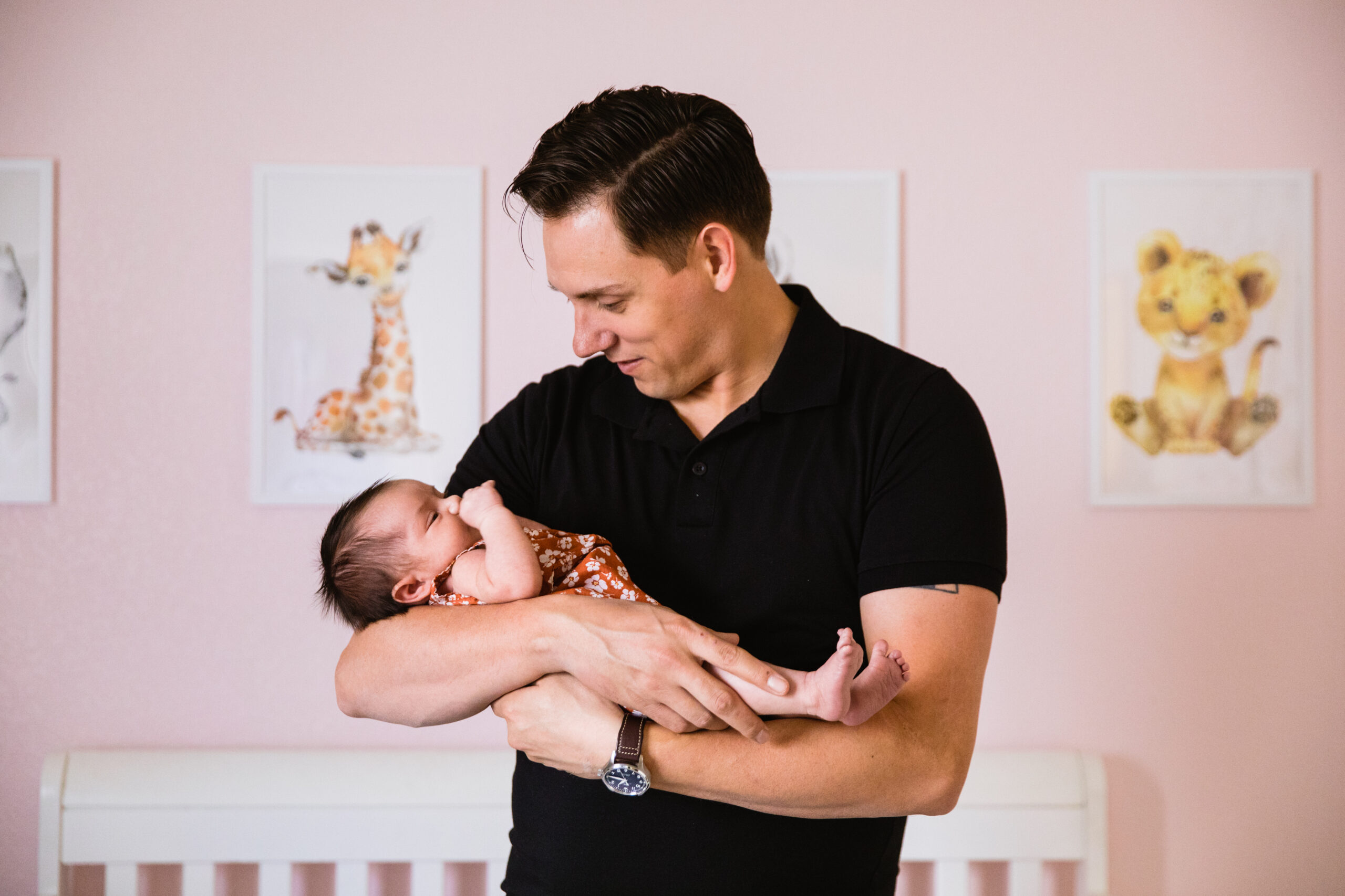 Newborn in her father's arms during their in-home newborn Phoenix family session by Arizona family photographer Juniper and Co Photography.