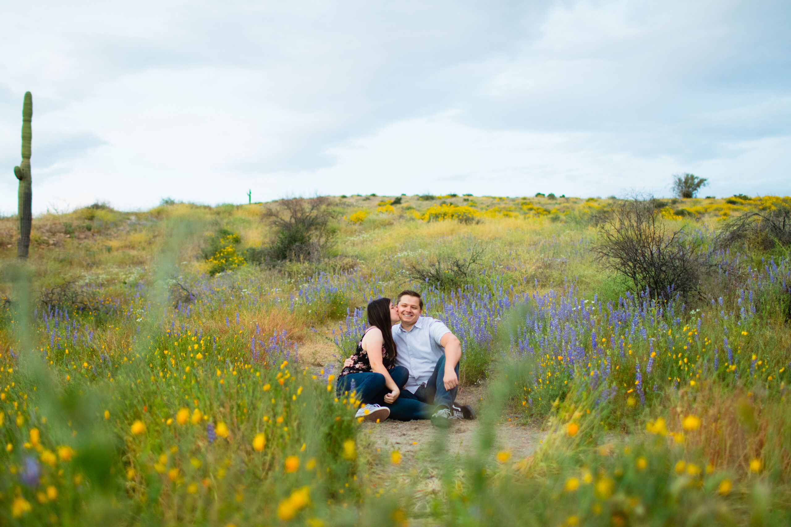 Boho couple pose for their desert wildflower engagement session by Arizona wedding photographer Juniper and Co Photography.