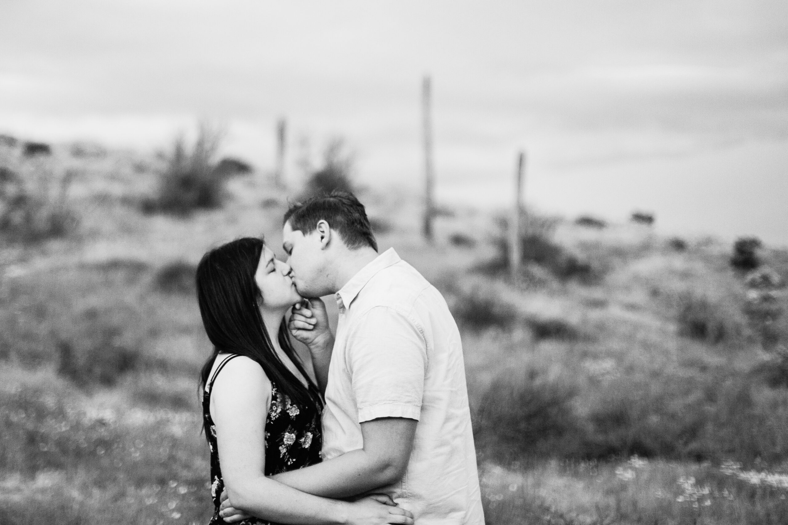 Boho couple share a kiss during their desert wildflower engagement session by Arizona wedding photographer Juniper and Co Photography.
