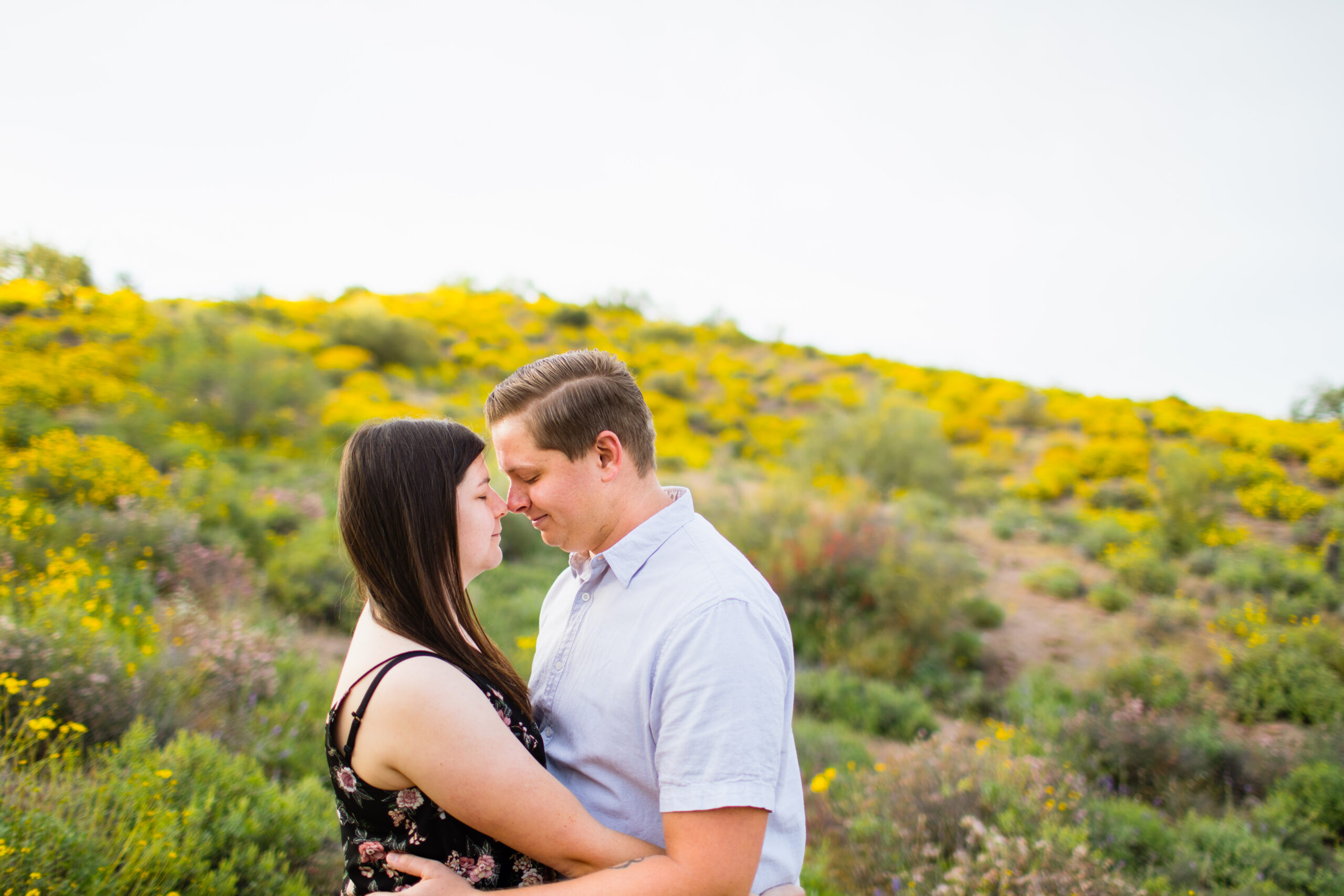 Couple share an intimate moment during their desert wildflower engagement session by Arizona engagement photographer Juniper and Co Photography.