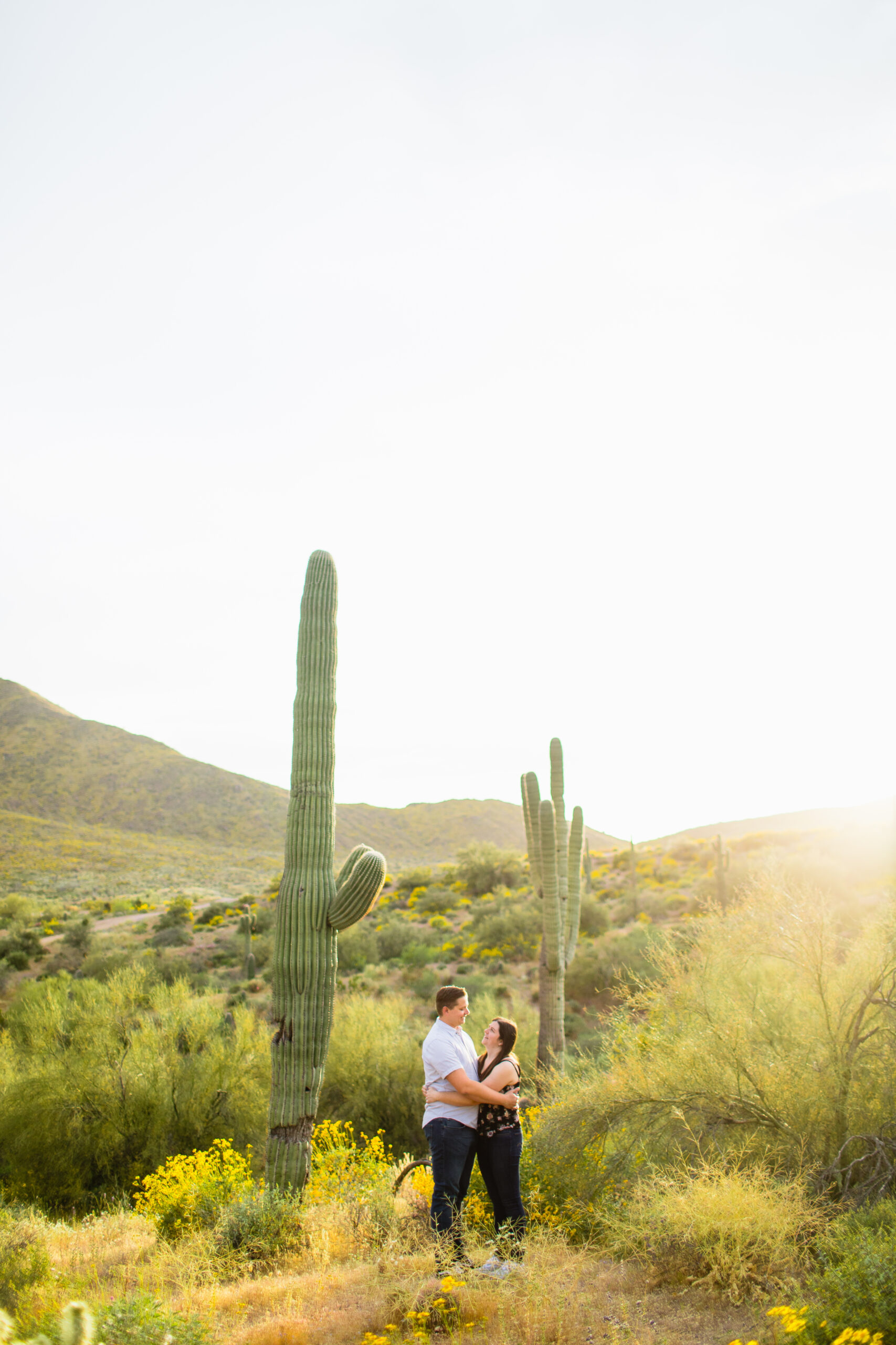 Couple look at each other during their desert wildflower engagement session by Arizona wedding photographer Juniper and Co Photography.