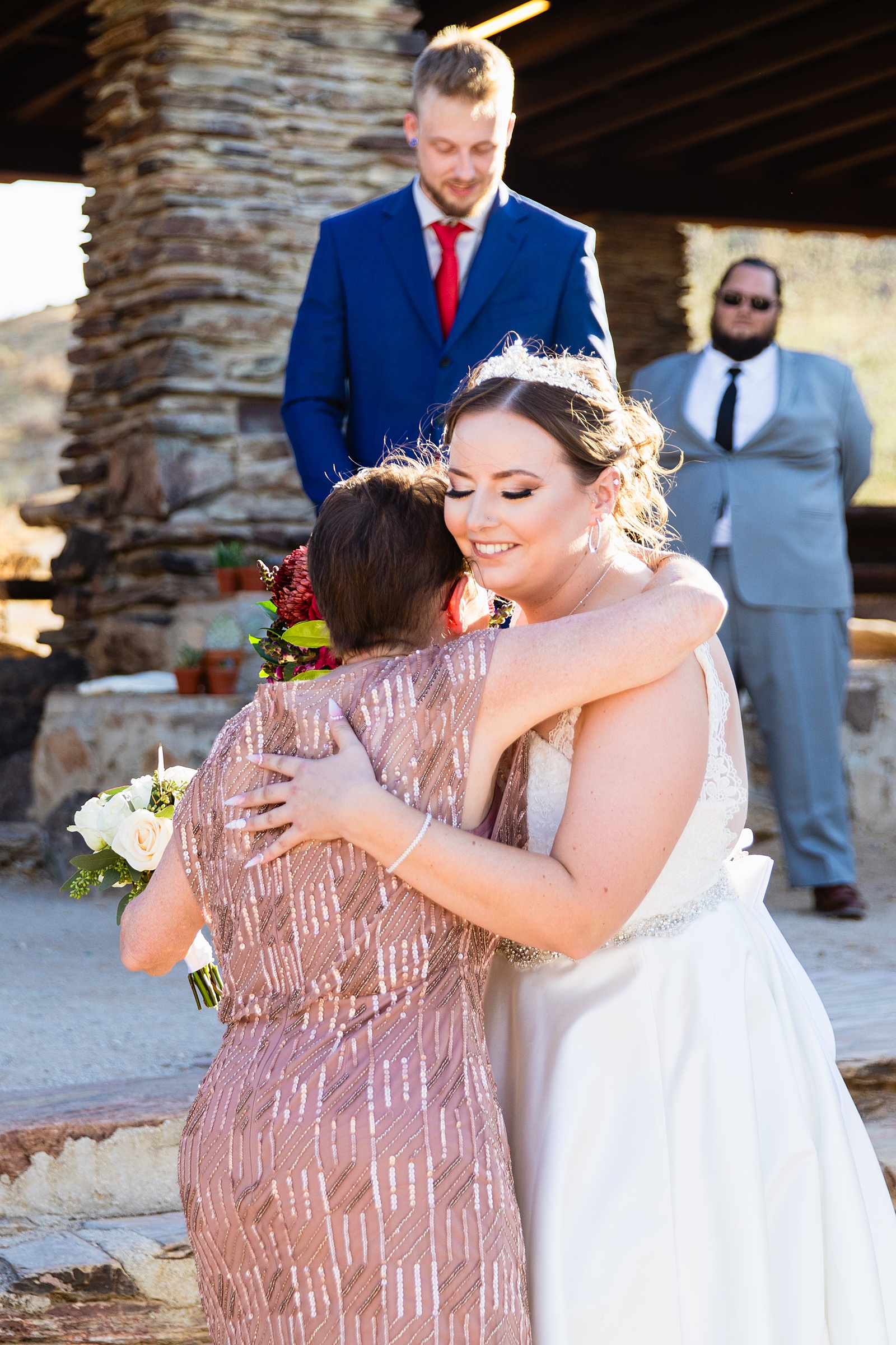 Bride shares a hug during intimate desert wedding ceremony by Phoenix wedding photographer Juniper and Co Photography.