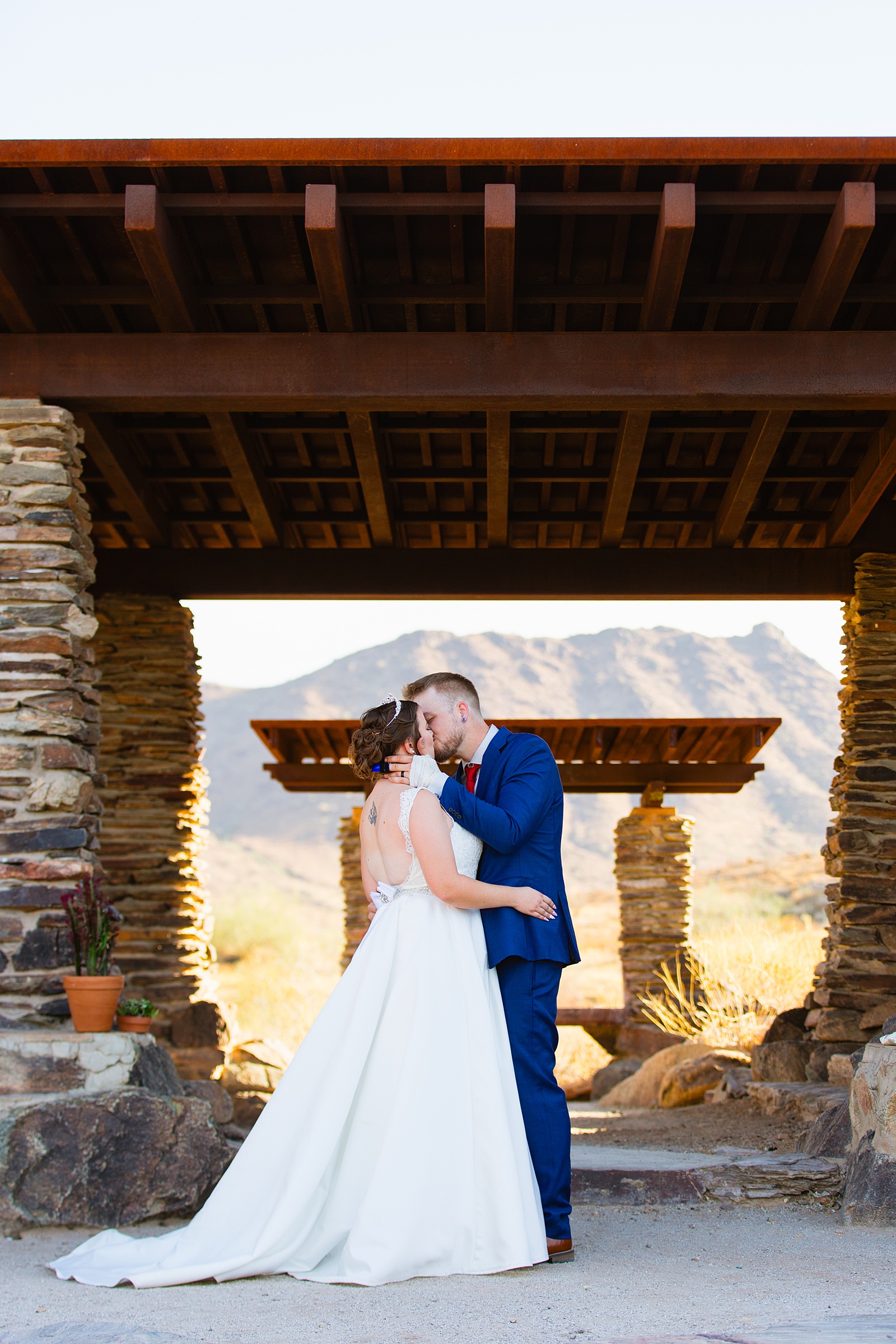 Bride and groom share their first kiss during their wedding ceremony at intimate desert by Arizona wedding photographer Juniper and Co Photography.