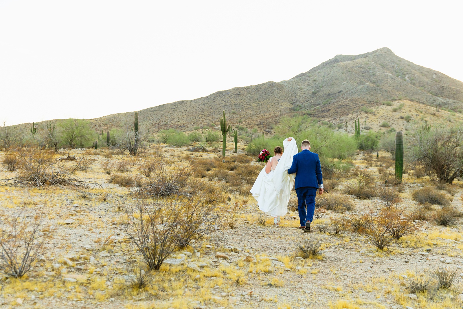 Bride and groom walking together during their intimate desert wedding by Phoenix wedding photographer Juniper and Co Photography.
