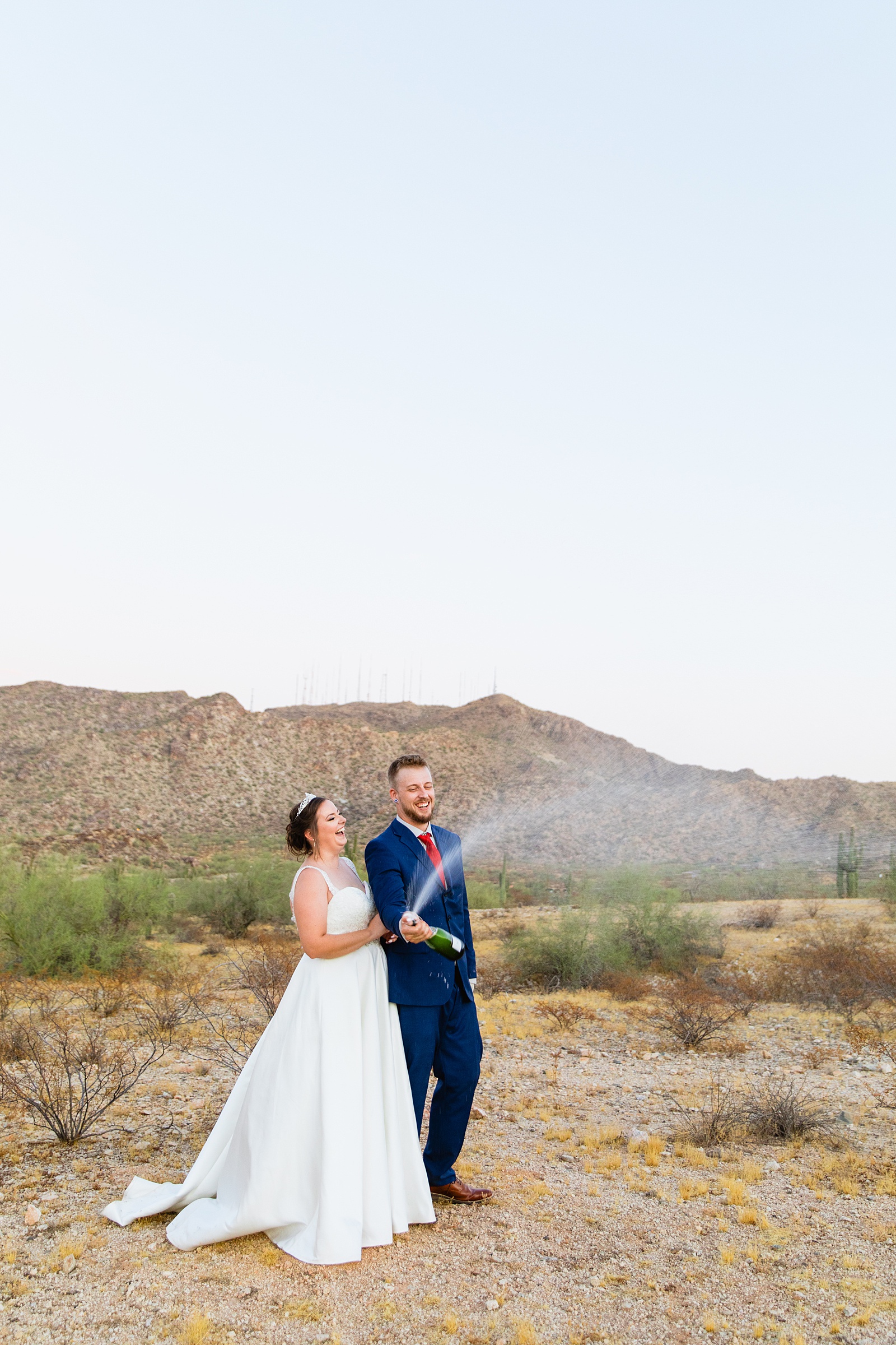 Bride and groom popping champagne together during their intimate desert wedding by Arizona wedding photographer Juniper and Co Photography.
