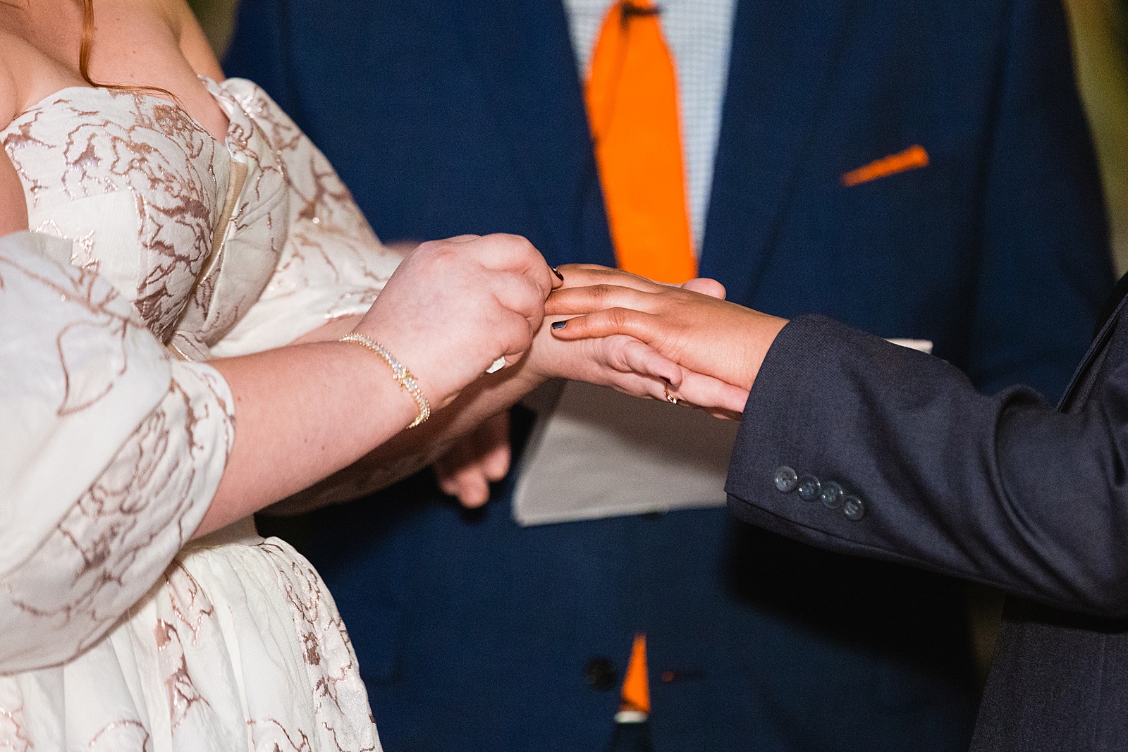 Same sex couple exchange rings during their wedding ceremony at Regency Garden by Phoenix wedding photographer Juniper and Co Photography.