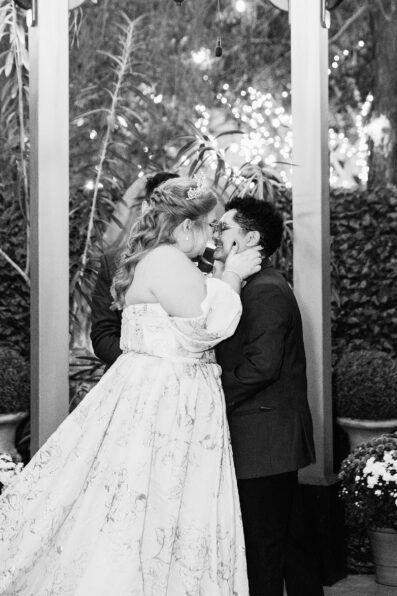 Same sex couple share their first kiss during their wedding ceremony at Regency Garden by Arizona wedding photographer Juniper and Co Photography.