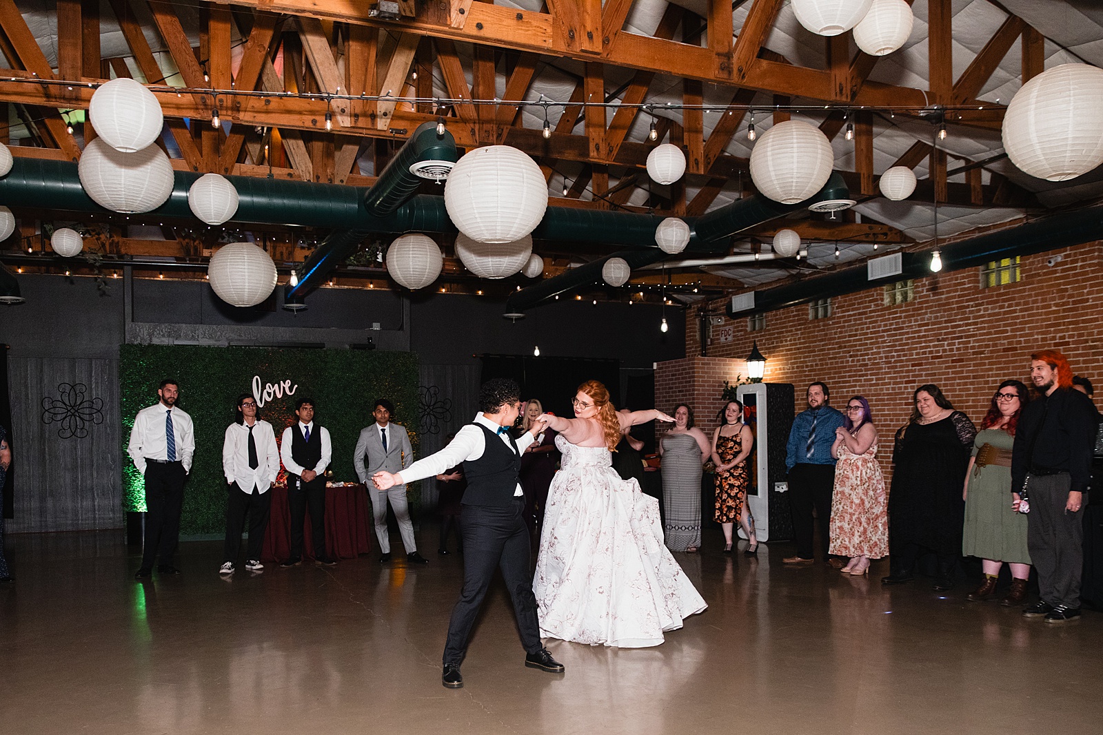Same sex couple sharing first dance at their Regency Garden wedding reception by Arizona wedding photographer Juniper and Co Photography.