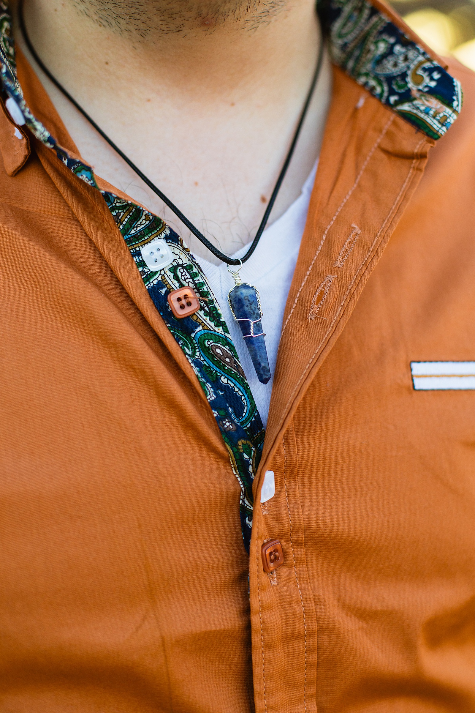 Groom's rust colored shirt and stone necklace detail for his Grand Canyon elopement by Juniper and Co Photography.