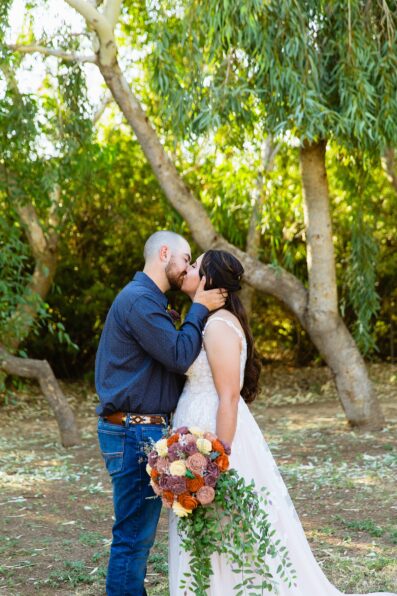 Bride & Groom share a kiss during their intimate backyard wedding by Arizona wedding photographer Juniper and Co Photography.