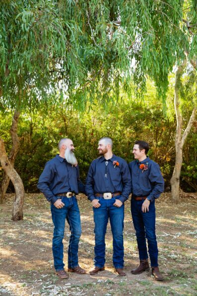 Groom and groomsmen laughing together at intimate backyard wedding by Phoenix wedding photographer Juniper and Co Photography.